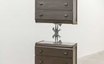 Two brown dressers with a metal piece holding on on top of the other.